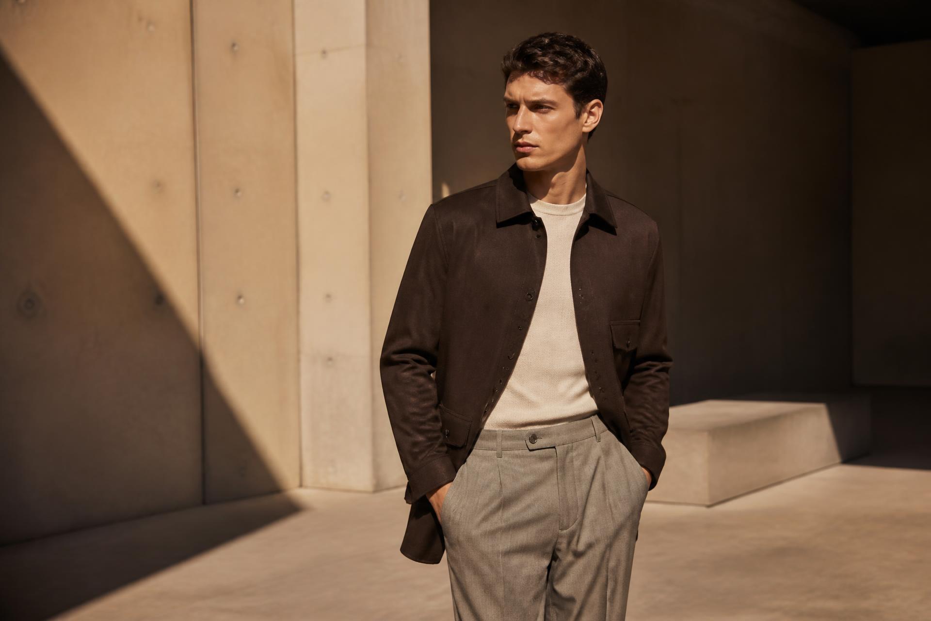 Mannlig modell i brun overshirt, kremstrikk og lyse bukser